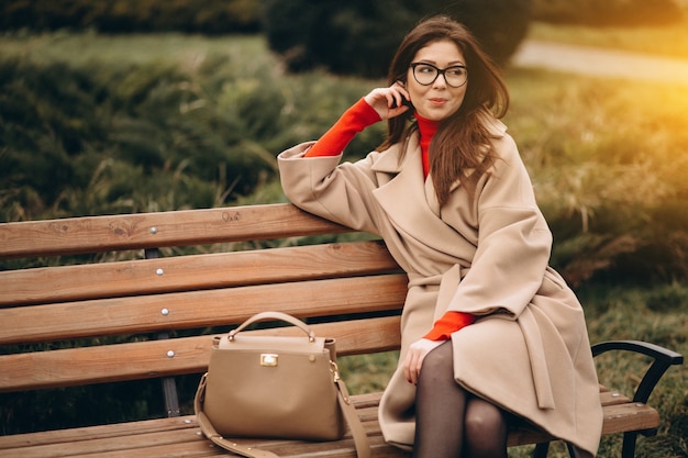 Mujer en abrigo beige sentado en un banco