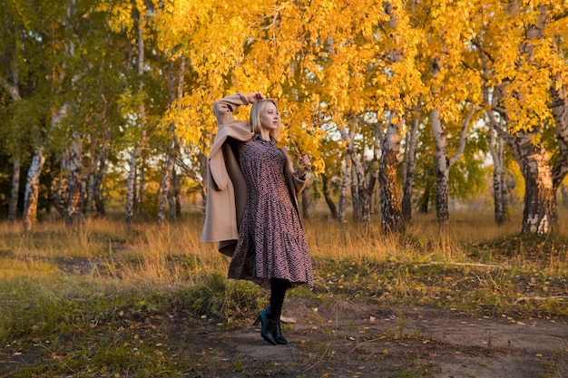 Mujer con un abrigo largo en el bosque de otoño