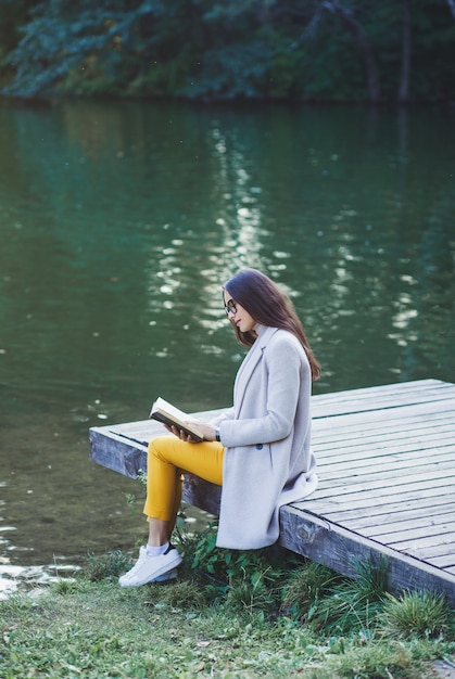 Mujer en abrigo leyendo un libro