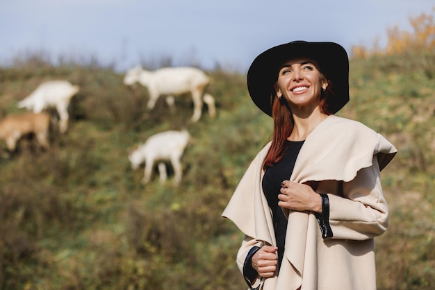 Mujer con abrigo y sombrero en el soleado día de otoño