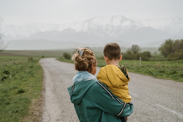 mujer abuela y su nieto viajan a lo largo de un camino con vistas a las montañas