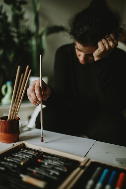 Mujer aburrida pintando en papel en la mesa
