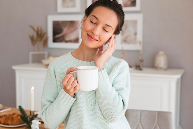 Foto mujer acogedora sosteniendo la taza en la cocina