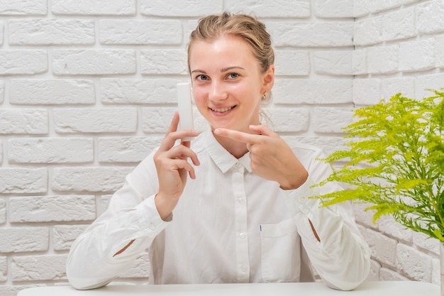 Mujer aconsejándole producto cosmético con fondo de pared de ladrillo blanco Cosméticos concepto de belleza y spa