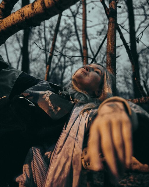 Foto mujer acostada en un árbol en el bosque