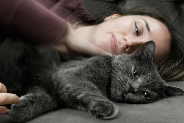 Mujer acostada en la cama con gato negro británico