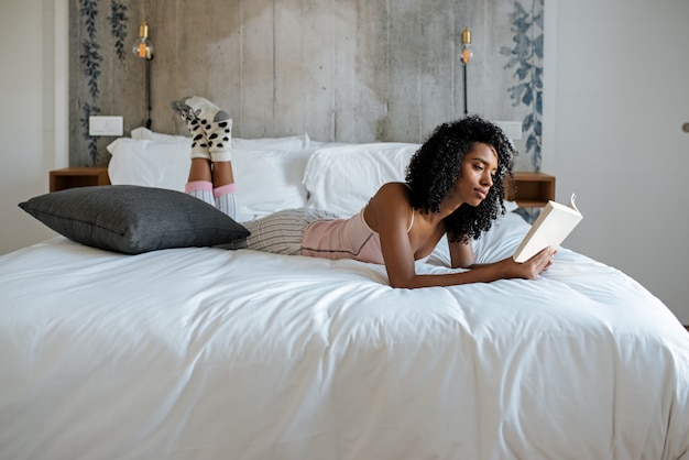 Mujer acostada en la cama leyendo un libro