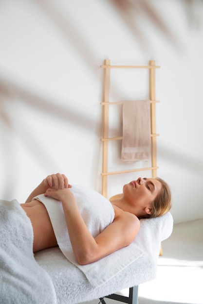 Foto mujer acostada en la cama de masaje lista para la sesión