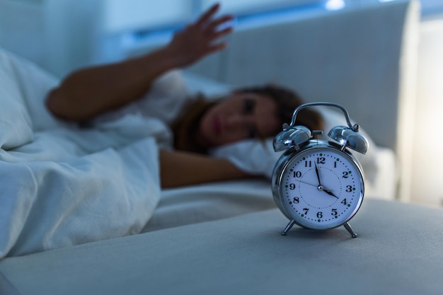 Mujer acostada en la cama que sufre de insomnio, insomnio y desesperada hermosa mujer caucásica despierta por la noche sin poder dormir, sintiéndose frustrada y preocupada sufriendo de insomnio en el trastorno del sueño