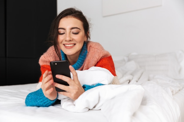 mujer acostada en la cama con smartphone