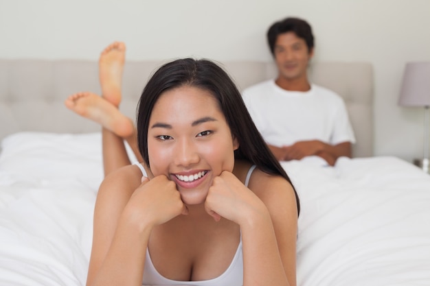 Mujer acostada en la cama sonriendo a la cámara