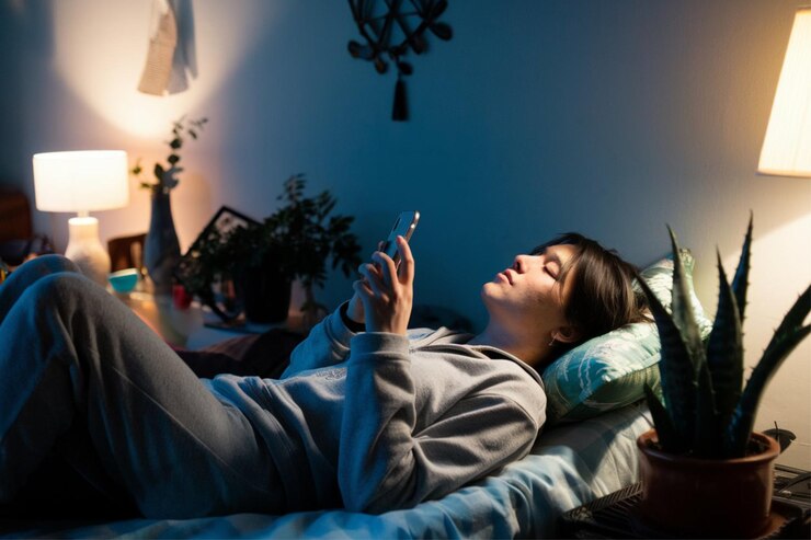 Foto una mujer acostada en una cama con un teléfono en la mano