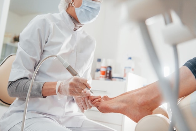 Mujer acostada y operada en los pies por un trabajador profesional de la clínica
