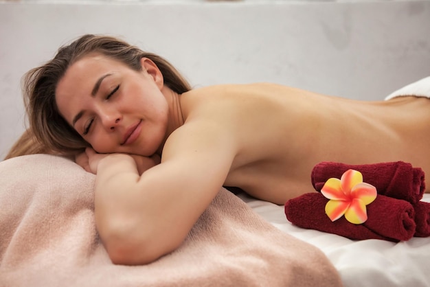 Mujer acostada en el salón de masajes SPA esperando a un terapeuta de masajes para hacer masajes de terapia de espalda y hombros