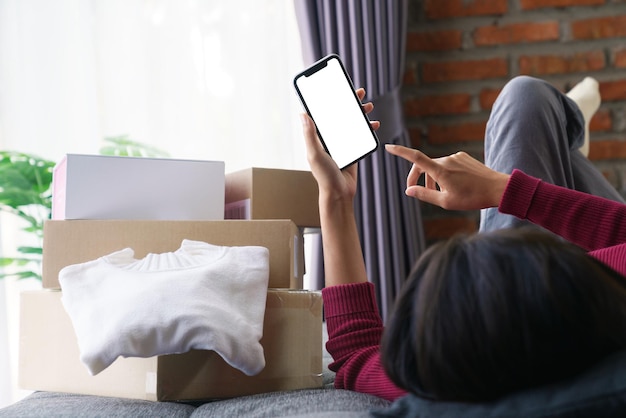 Mujer acostada en el sofá jugando con el teléfono de compras en línea