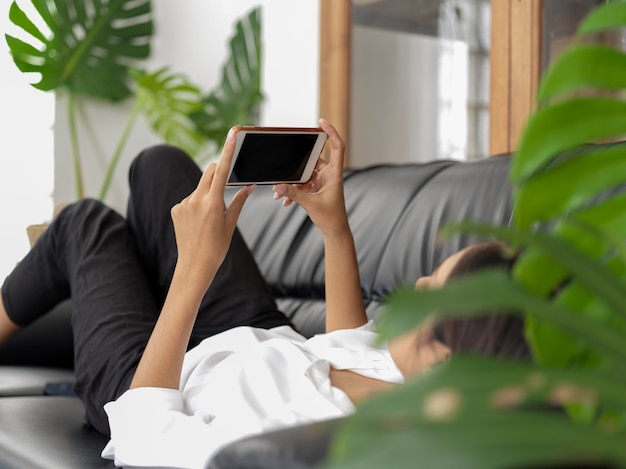 Mujer acostada en el sofá y con smartphone