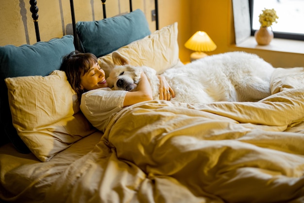 Mujer acostada con su enorme y lindo perro en la cama