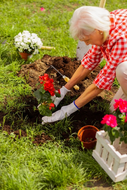 Mujer activa canosa naturaleza amorosa plantar flores cerca de casa