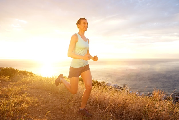 Mujer activa corriendo al aire libre durante la puesta de sol