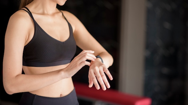 Una mujer activa está utilizando reloj inteligente en el gimnasio. Concepto de fitness y tecnología.