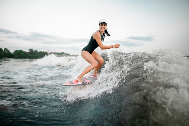 Mujer activa montando en el wakesurf sobre las rodillas dobladas