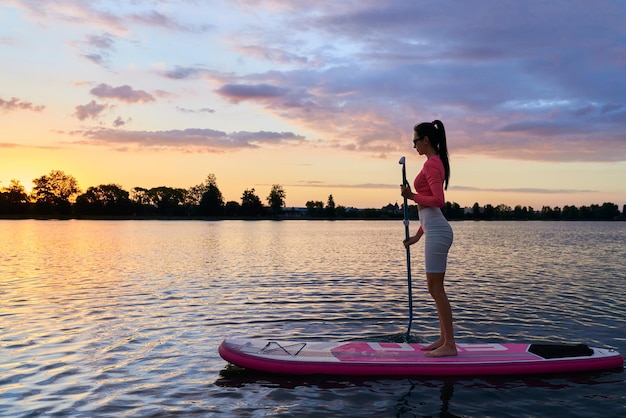 Mujer activa nadando a bordo de sup en el lago