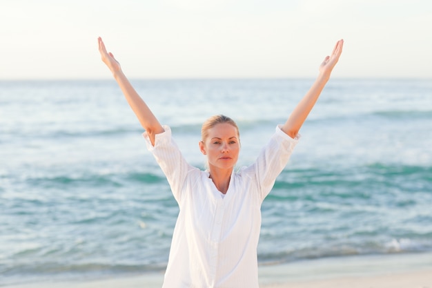 Mujer activa practicando yoga en la playa