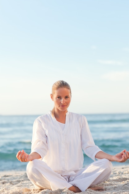 Mujer activa practicando yoga en la playa