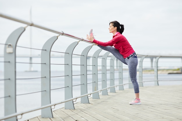 Mujer activa que se extiende en el muelle