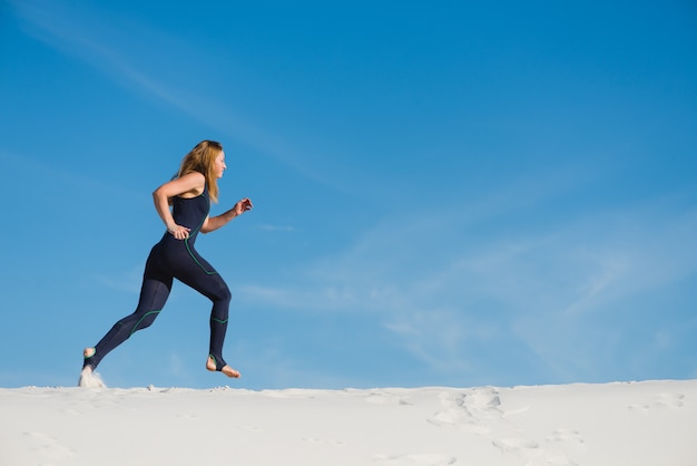 Mujer activa en ropa deportiva para correr en el desierto