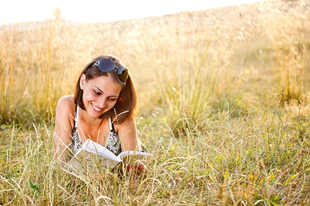 La mujer se acuesta en la hierba y lee el libro