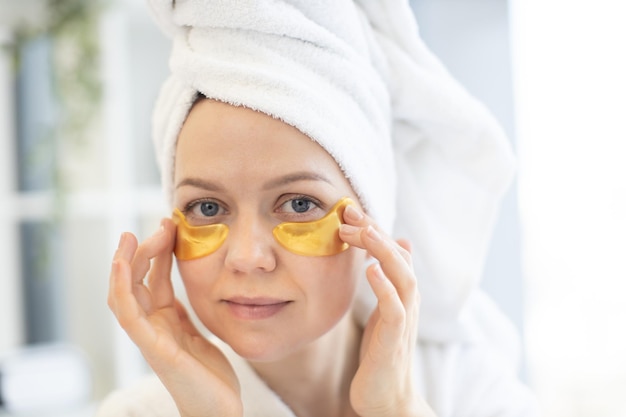 Mujer adaptando mascarillas de gel al contorno de ojos en casa