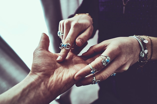 Mujer adivina con anillos de plata con piedra turquesa y pulseras lee líneas de palma durante la adivinación y predicción del futuro. Quiromancia y adivinación oculta