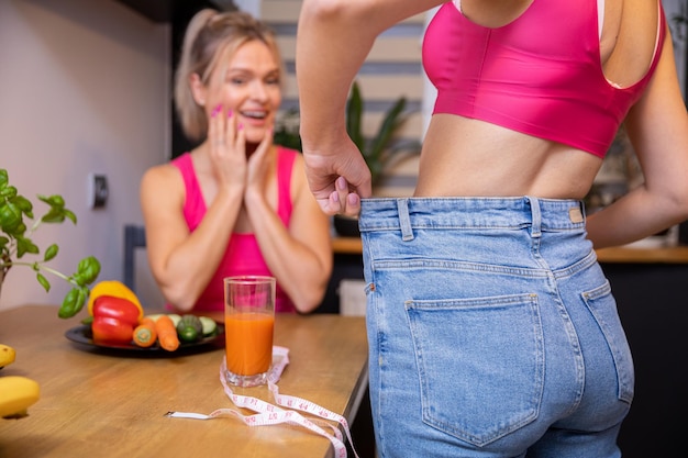 La mujer admira los resultados de pérdida de peso de sus amigas mientras está en la cocina