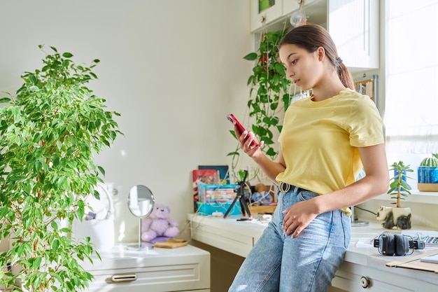 Mujer adolescente feliz usando un teléfono inteligente descansando en casa en el espacio de la copia de la habitación Tecnología de la adolescencia de estilo de vida concepto de juventud de las redes sociales de internet