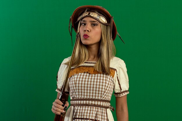 Foto mujer adolescente en foto de estudio con fondo verde haciendo poses y expresiones faciales vistiendo trajes típicos de festa junina