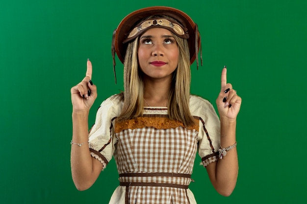 Foto mujer adolescente en foto de estudio con fondo verde haciendo poses y expresiones faciales vistiendo trajes típicos de festa junina