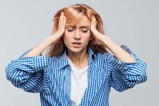 La mujer adolescente furiosa o estresante tiene dolor de cabeza, trata de concentrarse, se reúne con pensamientos, mantiene las manos en las sienes