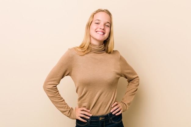 Foto mujer adolescente linda y natural confía en mantener las manos caderas.