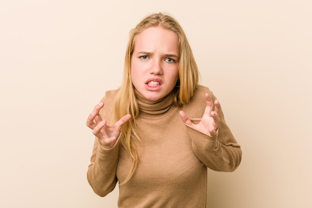 Mujer adolescente linda y natural molesto gritando con manos tensas.