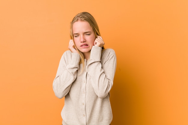 Mujer adolescente linda y natural que cubre las orejas con las manos.