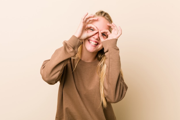 Mujer adolescente linda y natural que muestra bien firmar sobre los ojos