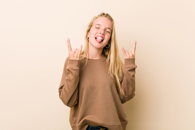 Mujer adolescente lindo y natural mostrando gesto de rock con los dedos
