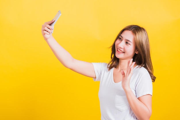 Mujer adolescente sonriendo de pie usar camiseta haciendo selfie foto videollamada en el teléfono inteligente