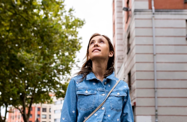 mujer adulta de 40 años mirando hacia el cielo nublado esperando sequía de lluvia en la ciudad