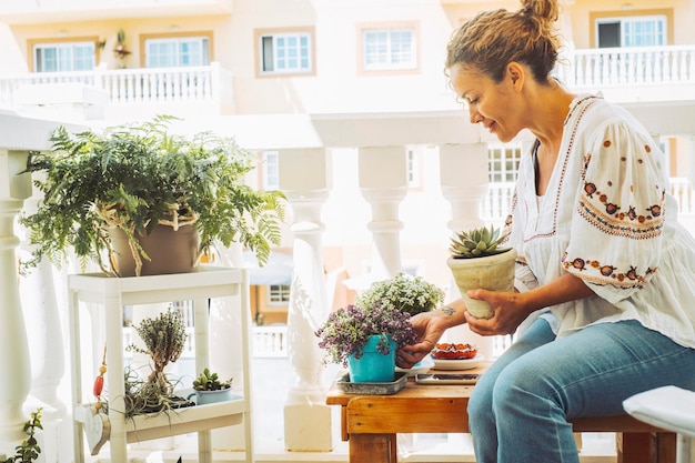 Mujer adulta en actividad de jardinería fuera de casa en la terraza Mujeres que cuidan las plantas para el medio ambiente y el concepto de estilo de vida verde Happy lady rebrote plantas afuera