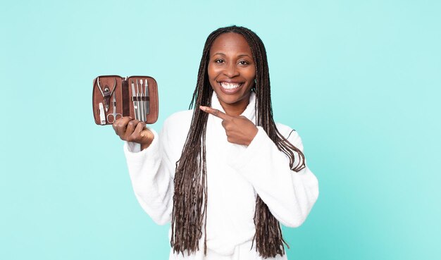 Mujer adulta afroamericana negra con bata de baño y sosteniendo una bolsa de maquillaje con herramientas nains