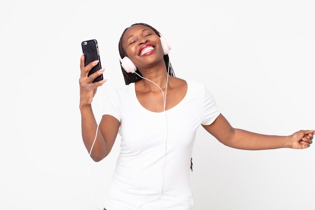 Mujer adulta afroamericana negra escuchando música con auriculares y smartphone