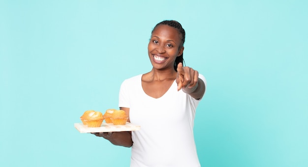 Mujer adulta afroamericana negra sosteniendo una bandeja de muffins