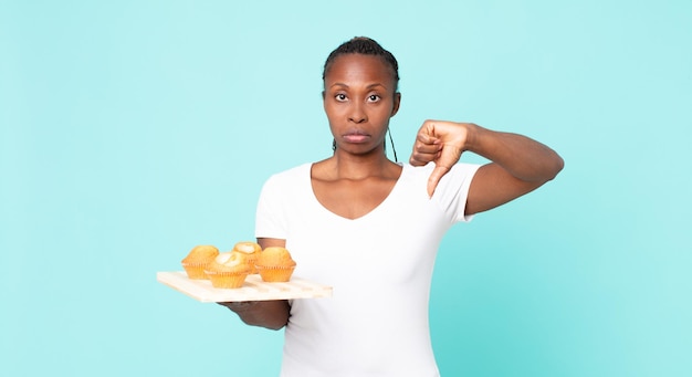 Mujer adulta afroamericana negra sosteniendo una bandeja de muffins